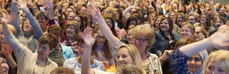 Happy crowd of teachers raising hands