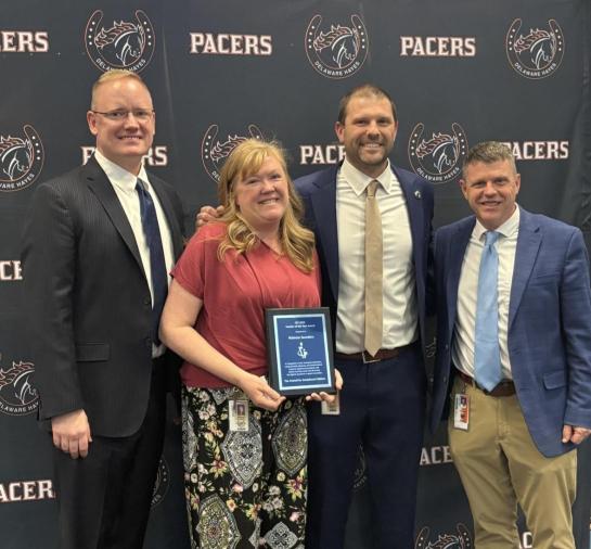 Picture of CEC's 2026 Teacher of the Year holding an award with her principal, superintendent, and CEC ED Chad Rummel