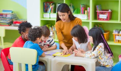 Image of a teacher sitting with a group of seated young students