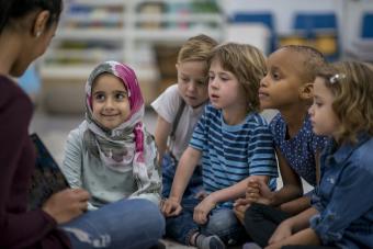 A teacher reads to a group of young students.