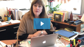 woman sitting at desk with big blue play button